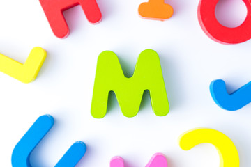 M letters in English made from wood bright colors.