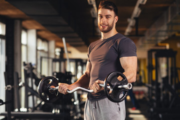 Handsome man doing biceps lifting in a gym