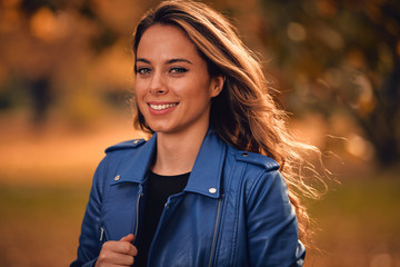 Cute smiley woman enjoying in autumn colored park.