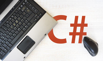 C sharp programming language,. laptop and vertical mouse on desk with C#