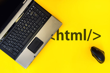 HTML Hyper Text Markup Language. laptop and vertical mouse on yellow background with html tag