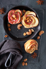 Three homemade puff pastries with rose shaped apple slices baked in cast iron skillet