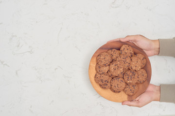 Plate of cookies in male hands on dark old wooden background top view