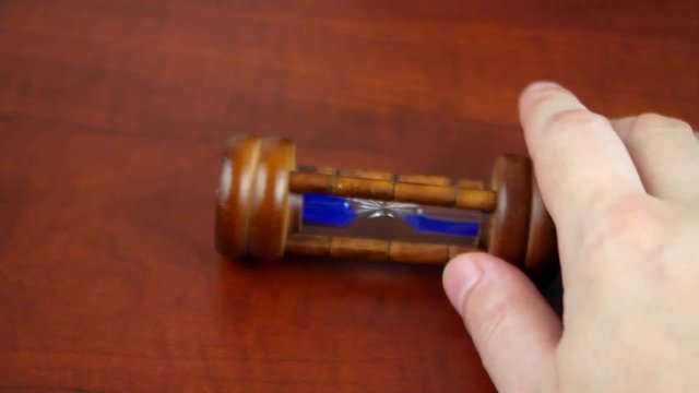 Stop time passing theme, men hand stops old hourglass on table