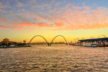 Gordijnen Toneellandschap van Elizabeth Quay Bridge op Swan River in Elizabeth Quay-jachthaven. De boogbrug is een nieuwe toeristische attractie in Perth, West-Australië. Hemel met rode wolken van zonsondergang. © bennymarty