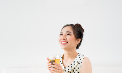 Young asian woman sitting on couch at home and drinking tea