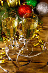 Two glasses of champagne and festive Christmas decorations on wooden table. Christmas and New Year celebration