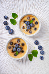 Creme brulee (cream brulee, burnt cream) with blueberry and lavender powdered with sugar on light