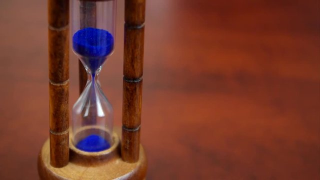 Time passing concept, vintage hourglass close up on wooden table with space for text
