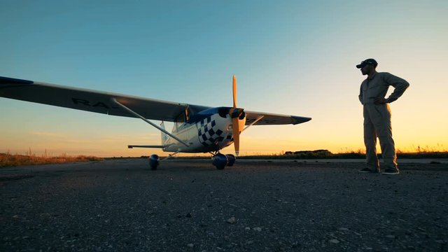 Flight engineer is looking at an aiplane in the open air.