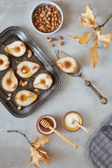 Obraz na płótnie Canvas Flat lay with a tray of baked pears with caramelized nuts on gray concrete background