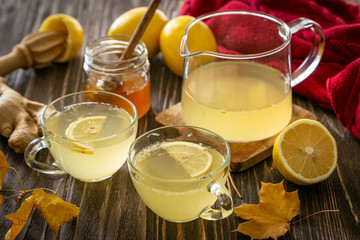 Autumn hot drink - ginger, lemon, honey tea and ingredients, wood back