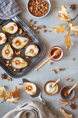 Flat lay with a tray of baked pears with caramelized nuts on gray concrete background