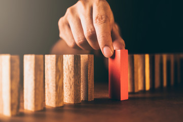 business man try to choose red color wood block from others on wooden table and black background...