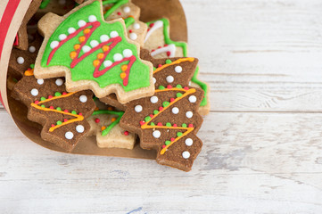 Tasty and cute baked Christmas cookies (gingerbread) with beautiful xmas decoration in paper bag on light wooden table background, close up, copy space (text space)