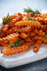 Baked butternut squash fries with sea salt and rosemary. Pumpkin chips on white wooden board.