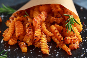 Baked butternut squash fries with sea salt and rosemary in paper cone. Pumpkin chips