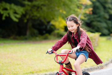 Fototapeta na wymiar 赤い自転車に乗る女の子