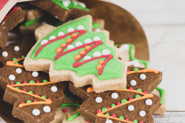 Tasty and cute baked Christmas cookies (gingerbread) with beautiful xmas decoration in paper bag on light wooden table background, close up, copy space (text space)