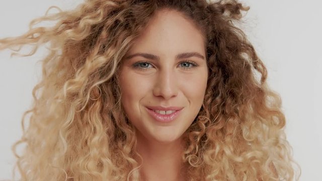 happy smiling laugnig model in studio. slowmotion from 60 fps. Curly blonde hair