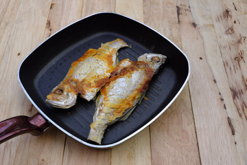 Fried fish in pan, bass cooking, copy space