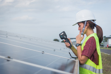 woman engineer checking heat of solar panel and using ir camera to scan heating of panel at solar...