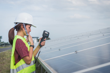 woman engineer checking heat of solar panel and using ir camera to scan heating of panel at solar power plant ; infrared camera using for checking and maintenance power plant of solar