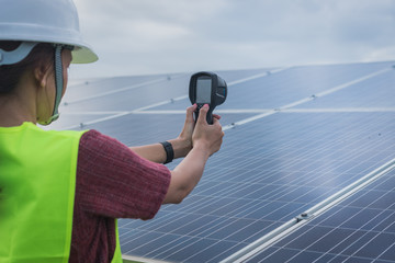 Obraz premium woman engineer checking heat of solar panel and using ir camera to scan heating of panel at solar power plant ; infrared camera using for checking and maintenance power plant of solar