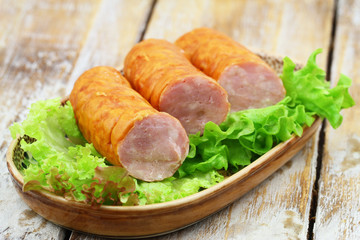 Plate of traditional Polish pork sausage on lettuce on plate on wooden surface
