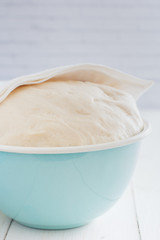 Yeast fresh raw dough in a blue bowl, selective focus