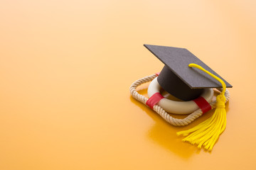 Graduation cap on lifebuoy or lifeguard and yellow background. Education reform due to digital disruption or innovation technology concept. University degree is not important in future. Need to help. - obrazy, fototapety, plakaty