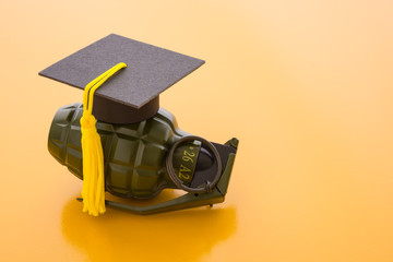 Graduation cap on hand bomb and yellow background. Education reform due to digital disruption or...