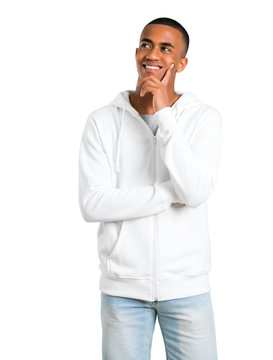 Dark-skinned Young Man With White Sweatshirt Standing And Thinking An Idea While Looking Up On Isolated White Background