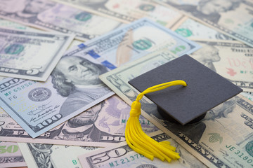 Graduation cap university or college degree on US dollars banknotes background. Education expense budget plan of money saving, loan, debt, personal loan, scholarship for studying abroad concept.