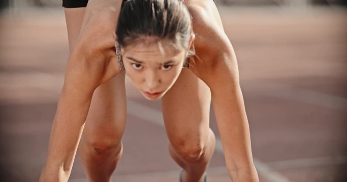 Female runner on track. Young asian athlete standing on starting line on stadium, then running forward, preparing for competition 4k