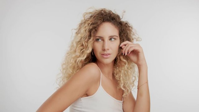 blonde curly hair caucasian model in studio on white background with streaming hair by wind. Beauty video for tutorial, hair tutorial