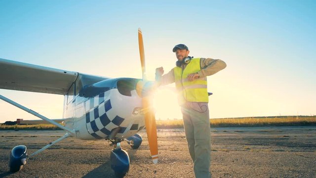 A pilot is standing beside a cropduster on a runway in an open field