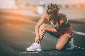 Close up portrait of sporty woman having knee injury in running track., Healthcare and sport concept. Sunshine background - obrazy, fototapety, plakaty