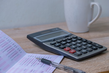 calculator,pencil , bankbook ,coffee cup  Put on a wooden table.