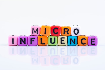 MICRO INFLUENCE word block concept on white reflection table