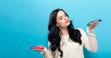 Young woman comparing two eye glasses on a blue background