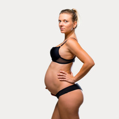 Obraz premium Blonde pregnant woman in underwear on isolated grey background