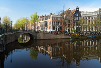 Historical houses and bridge over canal with mirror reflections, Amsterdam, Netherlands