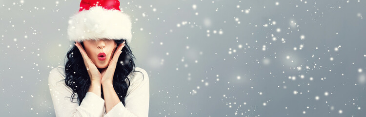 Woman with a Santa hat pulled over her eyes on a gray background