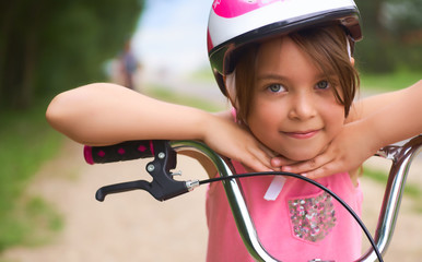 Close-up of a little girl's face on bike looking at camera and smiling