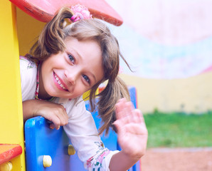 Adorable little girl wave his handsenjoying her time at the playground on warm and sunny summer day. Summer activities for little kids.