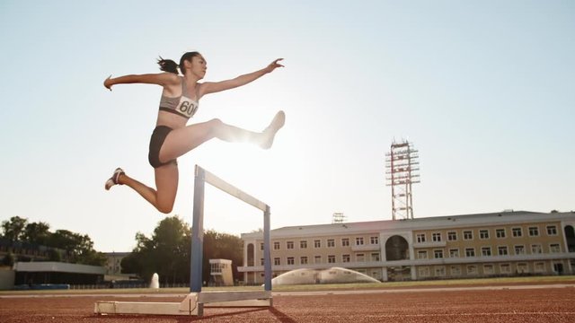 Female athlete on track. Young asian runner running on track of stadium, jumping over barriers, preparing for competition