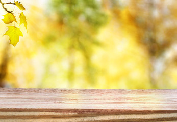 Naklejka na ściany i meble Wooden table with an autumn sky and foliage background