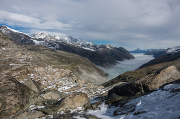 View to covered by clouds and mist  Stausee lake near Saas Fee in the southern Swiss Alps from Monte Moro pass, Italy