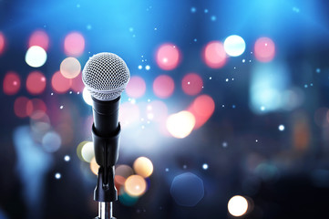 Microphone on stage ..Close up of microphone setting on stand with colorful light bokeh background in concert hall ,showbiz concept.